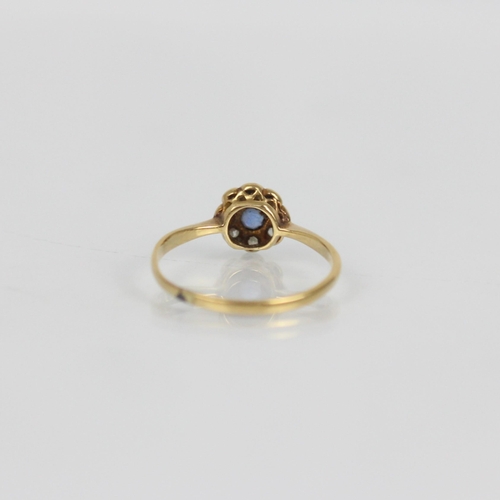114 - An early 20th century sapphire and diamond cluster ring, the central round cut sapphire within a sur... 