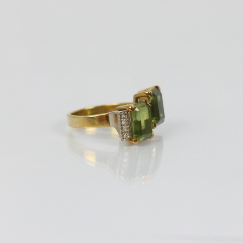 178 - A late 20th century green tourmaline and diamond ring, the two emerald cut green tourmalines set in ... 