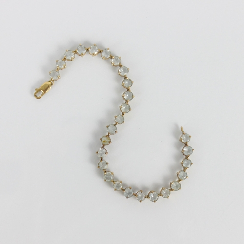 253 - A 9ct gold 'tennis' bracelet, the twenty seven pale blue stones set in claw setting edge, with lobst... 