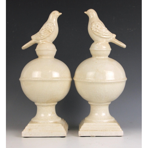 413 - A pair of modern white glazed pottery bird finials, the naturalistic birds atop stepped globes on sq... 