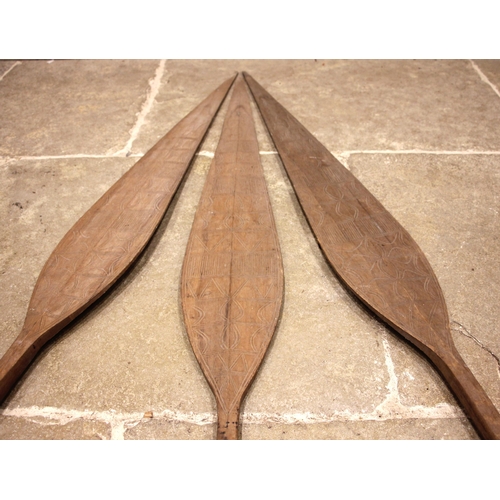 464 - Three Tribal Oceanic paddles, 20th century, each shaft handle leading to a leaf shaped terminal with... 