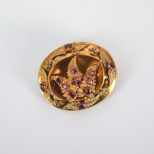 110 - An early/mid 19th century brooch, of oval form set with pink stones, possibly foil backed, within a ... 