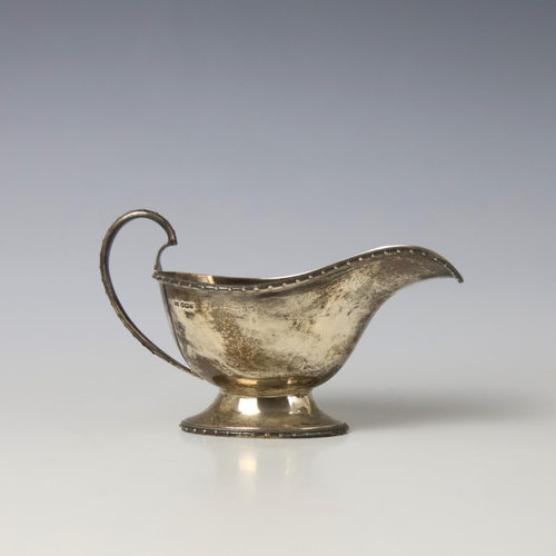 21 - A George V silver sauce boat, Walker & Hall, Sheffield 1933, the stylised beaded rim above plain pol... 