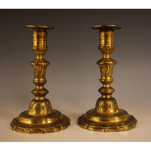 A pair of gilt brass Rococo style candlesticks, 19th century, the multi ...