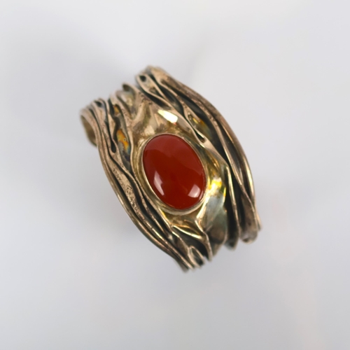 130 - A Mexican silver cuff, by Domingo, the central cabochon carnelian set within a fluid designed taperi... 