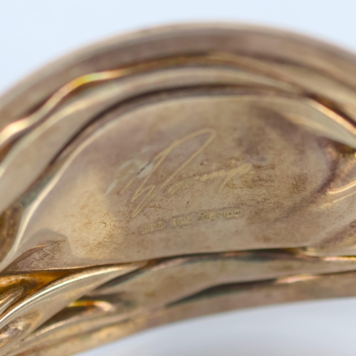 130 - A Mexican silver cuff, by Domingo, the central cabochon carnelian set within a fluid designed taperi... 