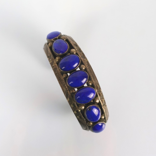 131 - A Navajo lapis lazuli cuff, the seven cabochon lapis lazuli within rub over setting leading to typic... 