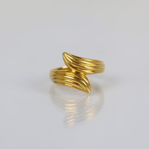 136 - A late 20th century yellow metal dress ring, the organically shaped ring with grooved tapering front... 