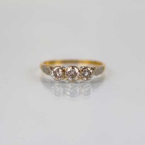 144 - A mid 20th century diamond three stone ring, the central round cut diamond with smaller diamond to e... 