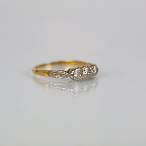 144 - A mid 20th century diamond three stone ring, the central round cut diamond with smaller diamond to e... 