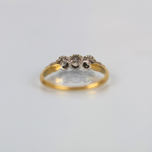 144 - A mid 20th century diamond three stone ring, the central round cut diamond with smaller diamond to e... 