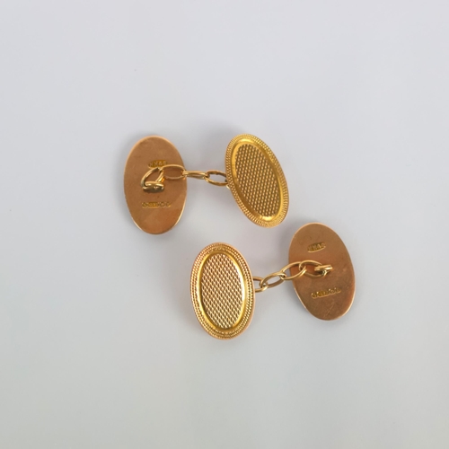 154 - A pair of early 20th century 9ct gold cufflinks, the oval links with engine turned decoration to fro... 