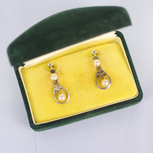 159 - A pair of Mikimoto pearl earrings, the white metal oval openwork drop encompassing pearl, surmounted... 