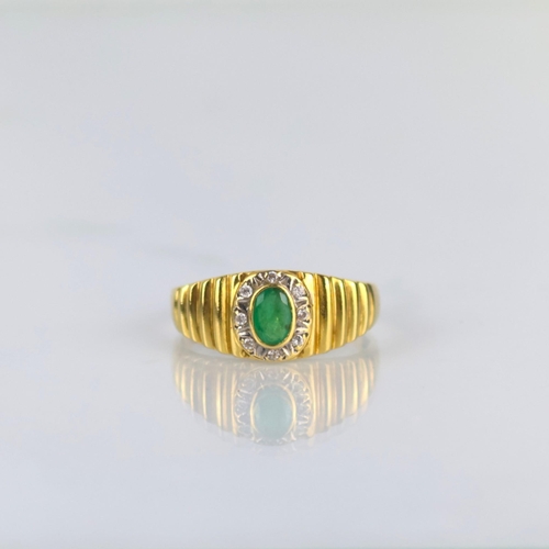 162 - A late 20th century emerald and diamond ring, the central oval cut emerald within surround of round ... 