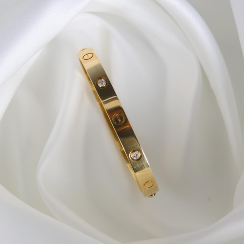 95 - A 'Cartier Love' bangle, the yellow gold bangle set with alternating screw head motifs and four diam... 
