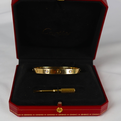 95 - A 'Cartier Love' bangle, the yellow gold bangle set with alternating screw head motifs and four diam... 