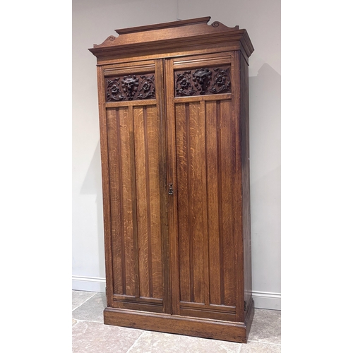 564 - A Victorian oak gentleman's compactum wardrobe, the pair of paneled and carved doors with inset foli... 
