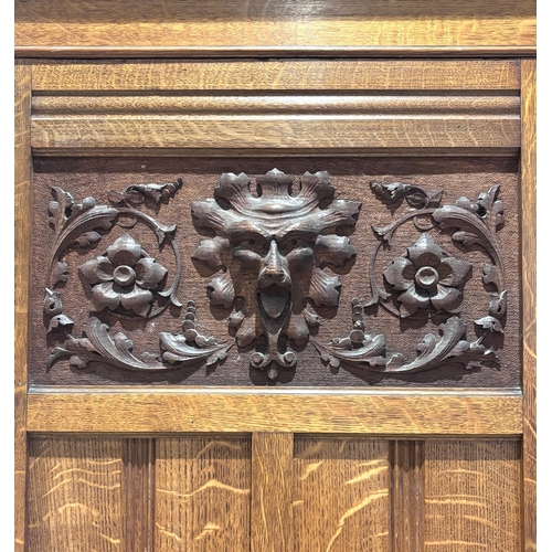 564 - A Victorian oak gentleman's compactum wardrobe, the pair of paneled and carved doors with inset foli... 