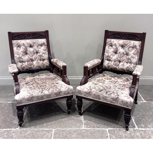581 - A pair of Victorian carved walnut library armchairs, each carved with floral motifs and aesthetic sp... 