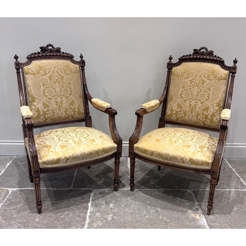 594 - A pair of Louis XVI style walnut fauteuils, the rails carved with a torch and quiver above a padded ... 