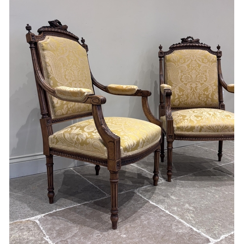 594 - A pair of Louis XVI style walnut fauteuils, the rails carved with a torch and quiver above a padded ... 
