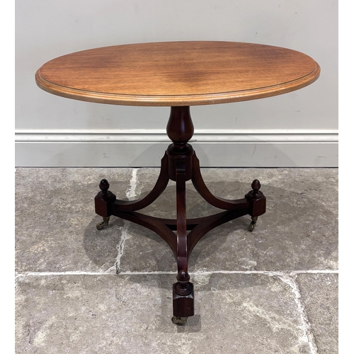 547 - A Regency style mahogany tilt top occasional table, the oval top above a turned column, extending to... 
