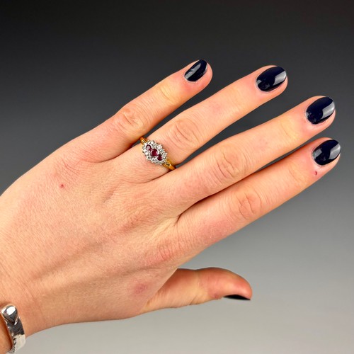 142 - A late 20th century 18ct yellow gold ruby and diamond dress ring, the central trio of round cut rubi... 