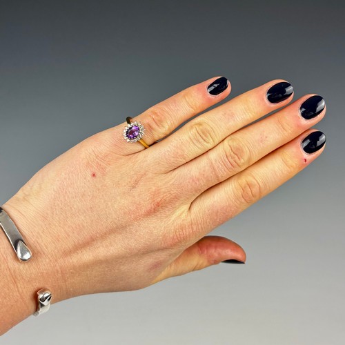 161 - A late 20th century 18ct yellow gold amethyst ring, the central oval cut amethyst within diamond sur... 