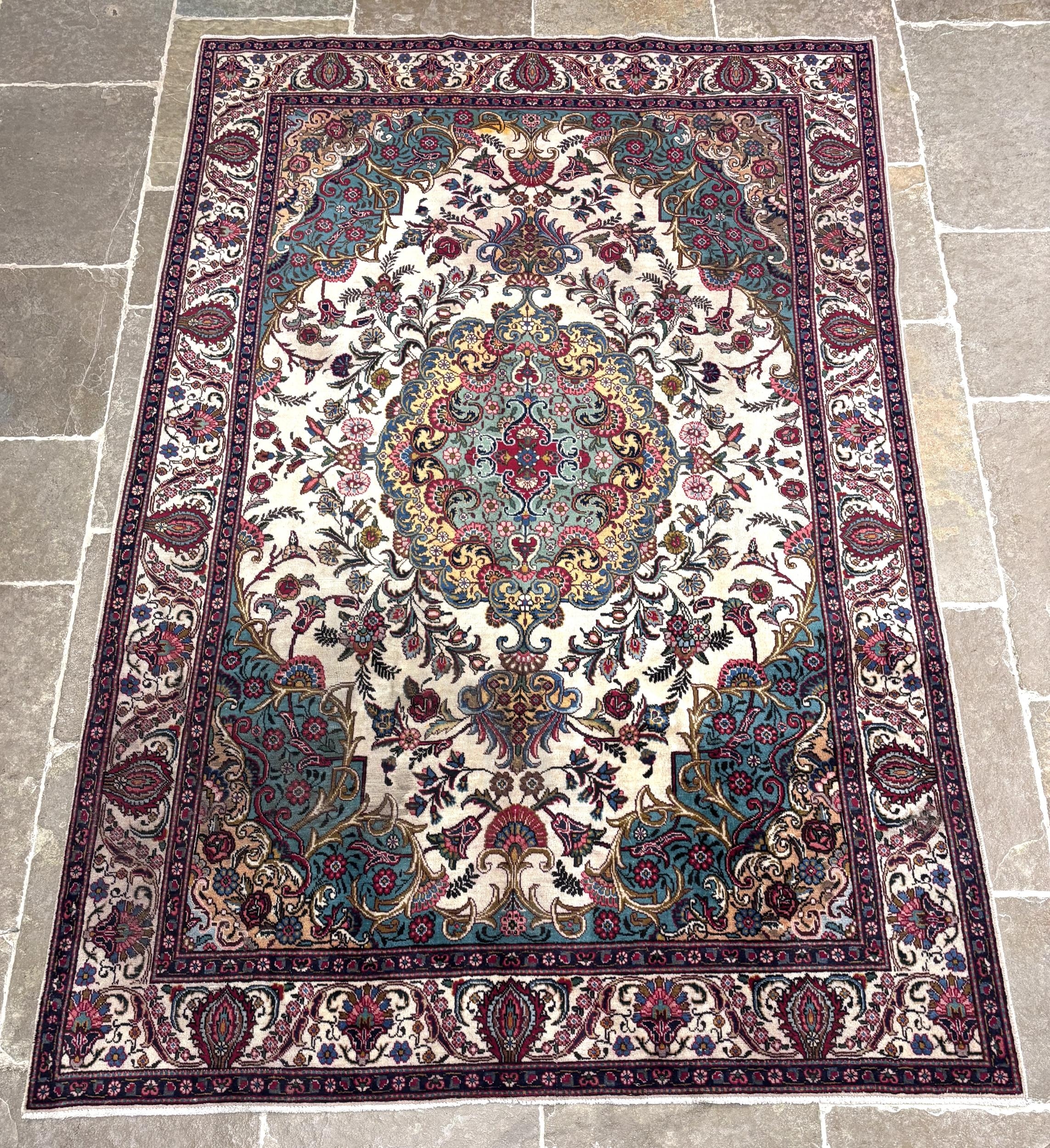 A large fine woven ivory ground Persian Tabriz carpet, with a central ...