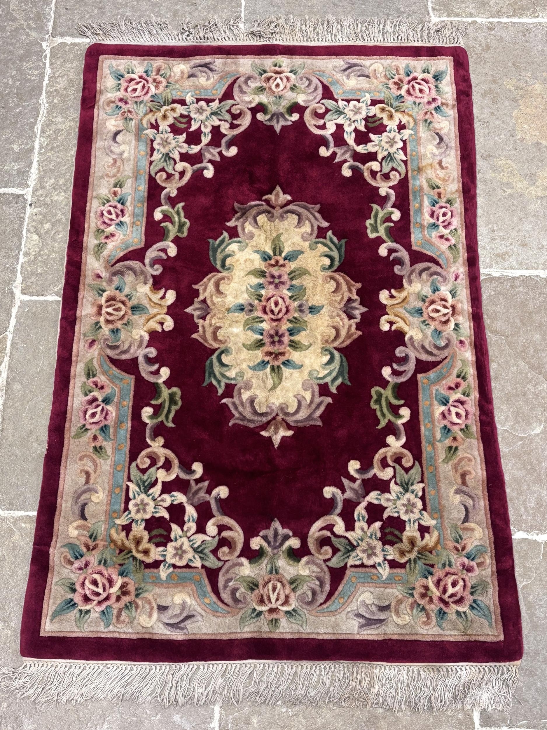 A red lotus Aubusson wool rug, against a claret ground with an ivory ...