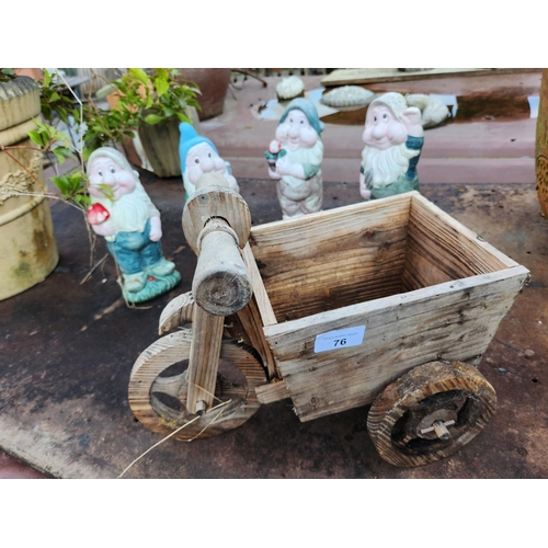 76 - A collection of four garden gnomes and a small wooden wheelbarrow