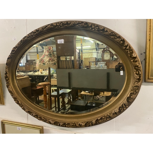 1143 - Large heavily framed oval mirror