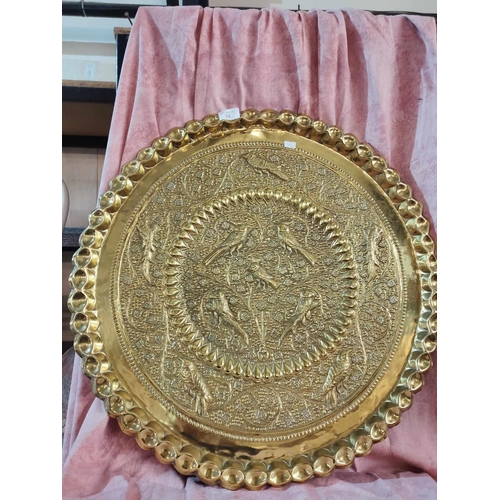 34 - A beautiful and large embossed brass tray with images of birds. Approx 2ft diameter