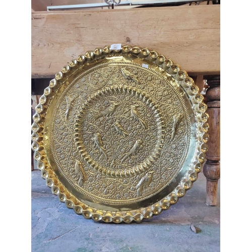 34 - A beautiful and large embossed brass tray with images of birds. Approx 2ft diameter