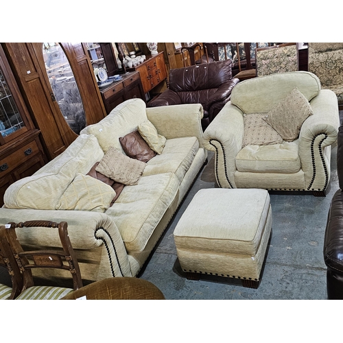 273 - Very large twin seater cream sofa with studded detail and matching armchair and footstool in fair co... 