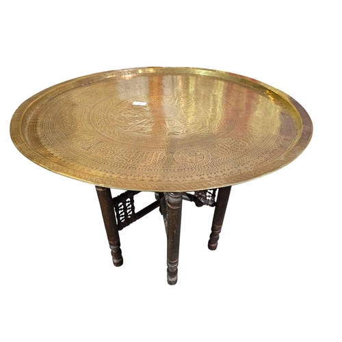 37 - Very large brass charger Indian influence on folding wooden turned legs 73cm in diameter