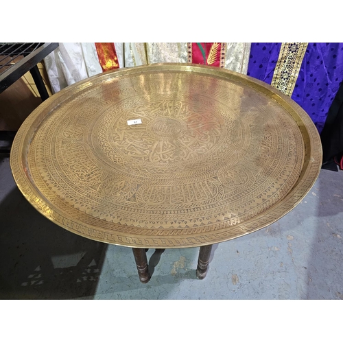 37 - Very large brass charger Indian influence on folding wooden turned legs 73cm in diameter