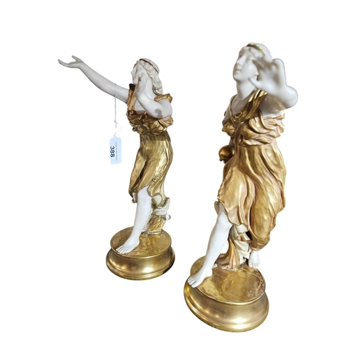 388 - A pair of Royal Worcester short gold porcelain figurines modelled as neo-classical ladies wearing di... 