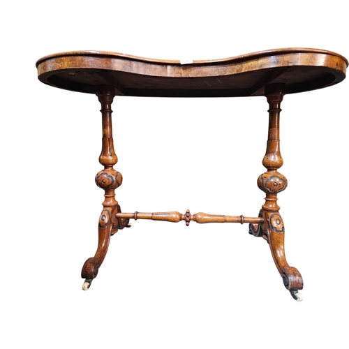 694 - A Victorian figured walnut kidney shaped writing table with green leather insert raised on turned an... 