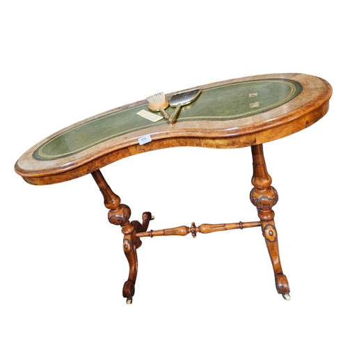 694 - A Victorian figured walnut kidney shaped writing table with green leather insert raised on turned an... 