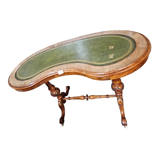 694 - A Victorian figured walnut kidney shaped writing table with green leather insert raised on turned an... 