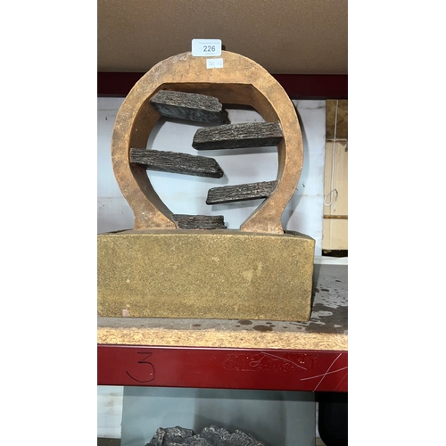 226 - tabletop water fountain featuring a circular frame and stacked stone accents.