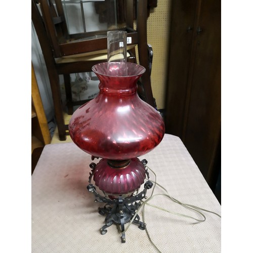 793 - Vintage oil lamp with red glass shade and glass chimney and ornate metal base which has been convert... 