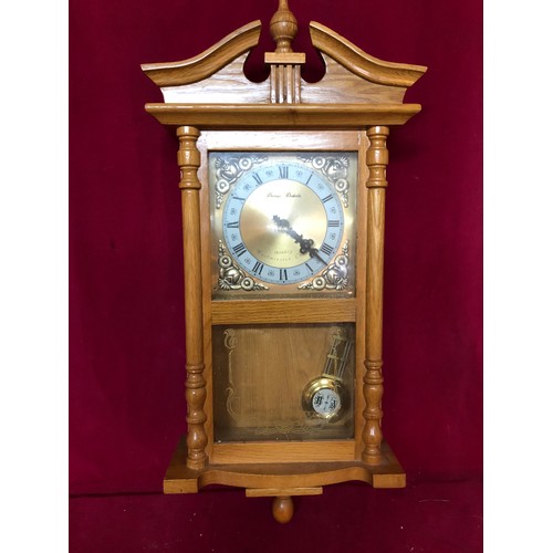 751 - A wall hanging Quartz clock with westminster chime in light wood by Daniel Dakota. Measures 62cms ta... 