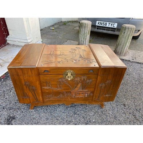 310 - Wooden camphor chest with carved Eastern scene measuring 100 x 59 with legs. Has wooden inset tray