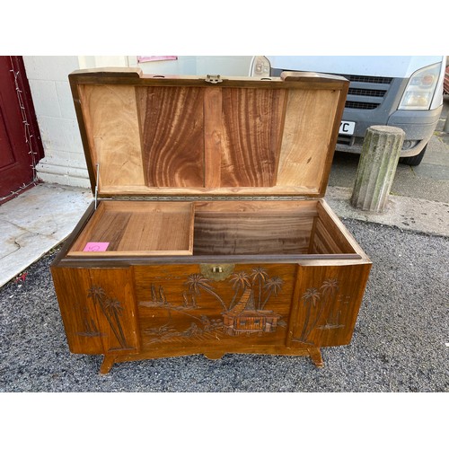 310 - Wooden camphor chest with carved Eastern scene measuring 100 x 59 with legs. Has wooden inset tray