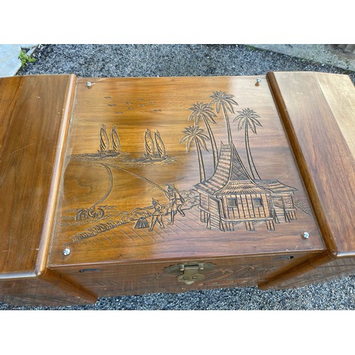 310 - Wooden camphor chest with carved Eastern scene measuring 100 x 59 with legs. Has wooden inset tray