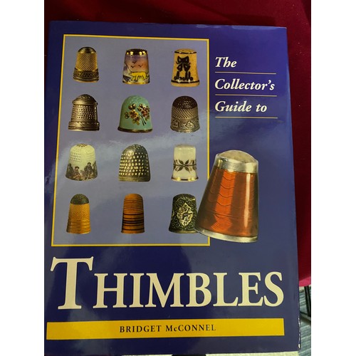 513 - Collection of 44 porcelain and metal thimbles on display holder accompanied with 2 books
