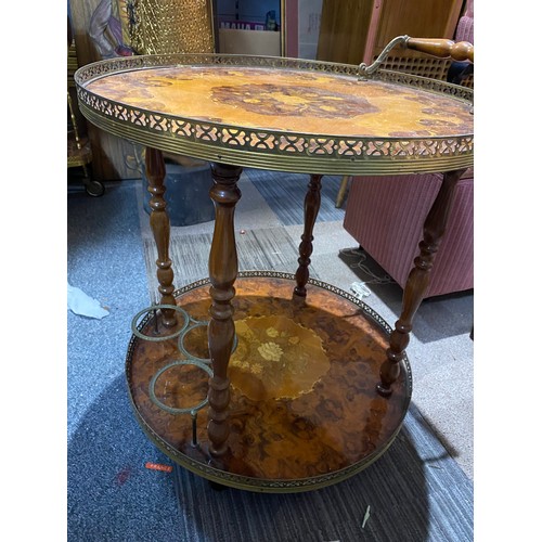 151 - Round drinks table with decorative inlay top and lower shelf, bottle holder and brass trim. 55x62cms