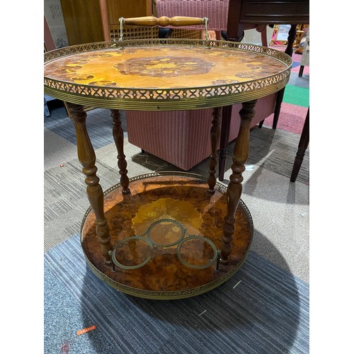 151 - Round drinks table with decorative inlay top and lower shelf, bottle holder and brass trim. 55x62cms